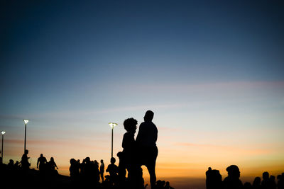 Silhouette of people enjoying the wonderful colorful sunset of farol da barra in salvador, bahia.