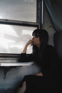 Side view of woman sitting in window