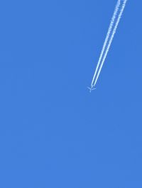 Low angle view of airplane flying against clear blue sky