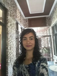 Portrait of smiling young woman standing against ceiling
