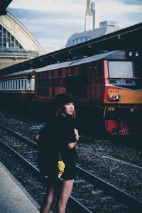 Young woman with backpack standing on railroad station platform