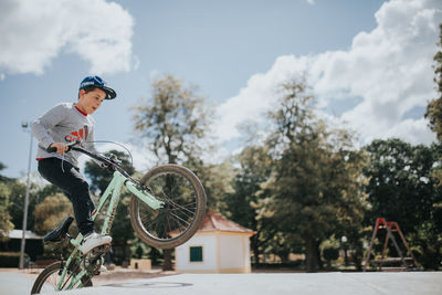 Side view of young man riding bicycle against trees