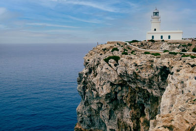 Lighthouse by sea against sky