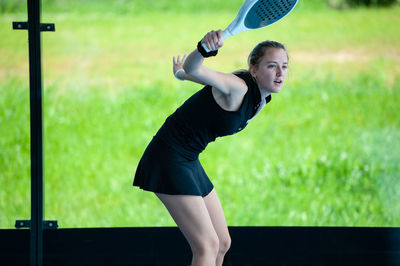 Side view of woman with arms raised on field