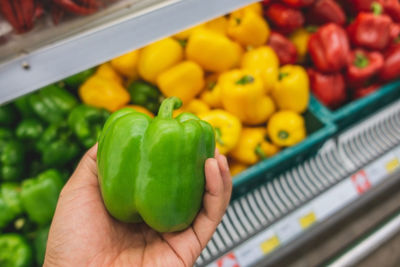 Cropped image of hand holding bell peppers at market