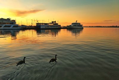 Silhouette boats in lake against sky during sunset