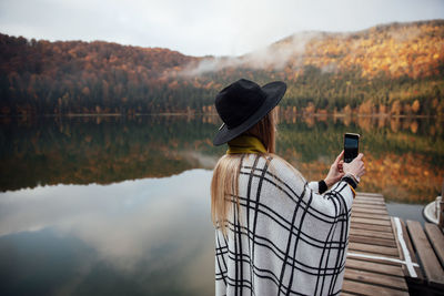 Hipster woman photographs sunset on smartphone. girl holding a mobile phone. autumn background