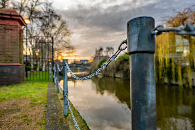 Metal fence by canal against sky