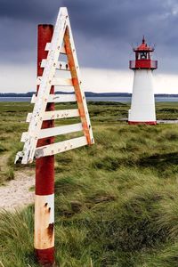 Lighthouse on field against sky