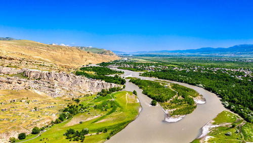 Scenic view of river amidst green landscape against blue sky