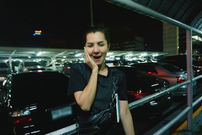 Surprised woman standing against railing at night