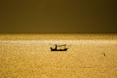 Silhouette of fishing boat on sea during sunset