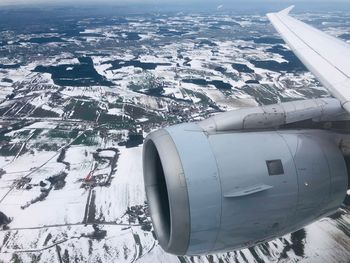 Aerial view of snowcapped landscape seen through airplane window