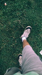Low section of person walking on grassy field
