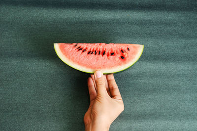 Close-up of hand holding watermelon slice