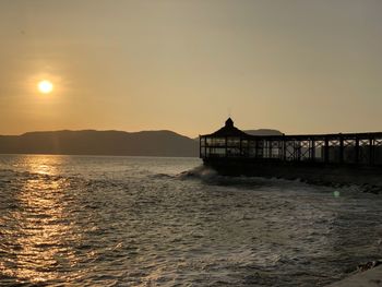 Silhouette pier over sea against sky during sunset