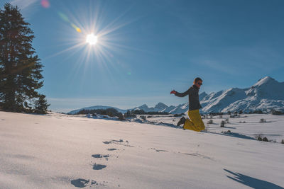 A full-body shot of a playful young caucasian woman jumping in the french alps mountains
