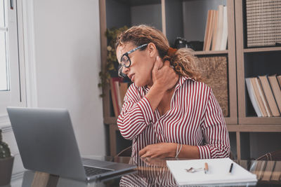 Woman using phone while sitting on table