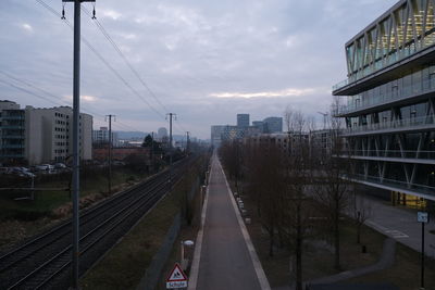 Railroad tracks amidst buildings in city against sky