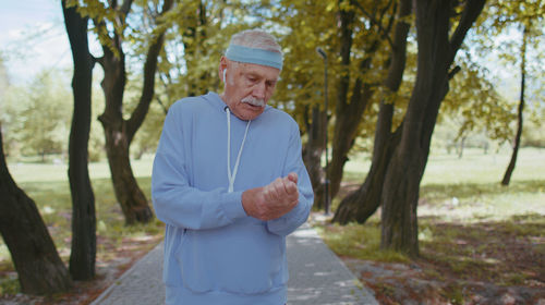 Exhausted senior man checking wrist in park