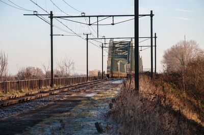 Railroad tracks by bare trees against sky