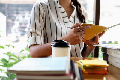 Midsection of woman reading book while sitting on table