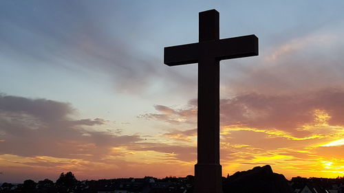 Silhouette cross against sky during sunset