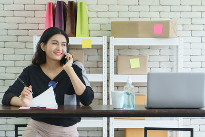 Portrait of a smiling young woman sitting on table