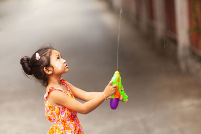 Side view of a smiling young woman holding outdoors