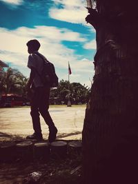 Rear view of man standing at beach against sky