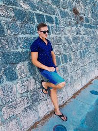 Full length of woman wearing sunglasses against wall