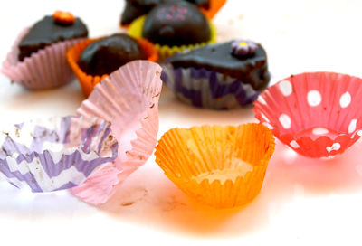 Close-up of cupcake holders by chocolate dessert over white table