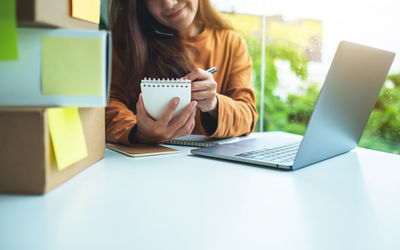 Midsection of woman using laptop on table