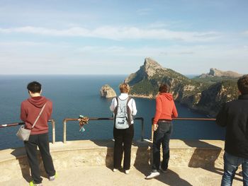 Rear view of people at observation point against sea