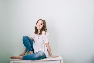 Portrait of smiling young woman sitting on chair at home