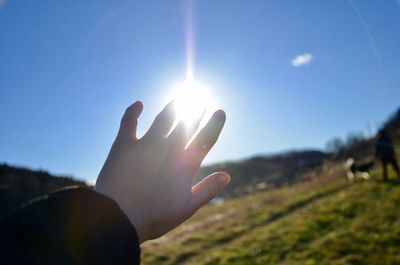 Optical illusion of cropped hand touching sun against sky