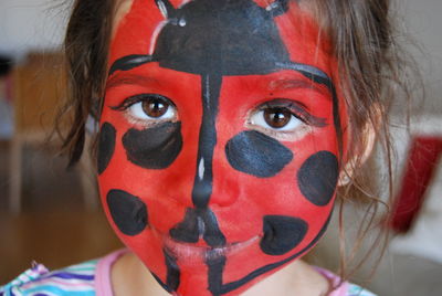 Portrait of girl with face painted as ladybug