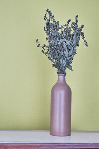 Close-up of flower vase on table against wall