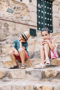 Sad siblings sitting on staircase in city