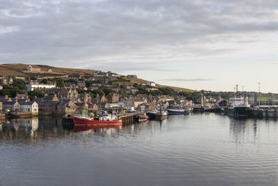 Boats moored at harbor against sky