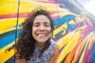 Portrait of smiling young woman against wall