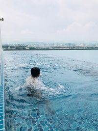 Rear view of person swimming in pool