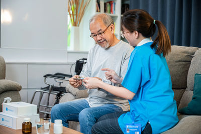 Side view of young woman using mobile phone while sitting at home