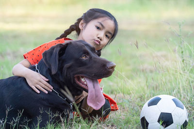 A lovely southeast asian child girl in red outfits plays with her big dog in the back or front yard