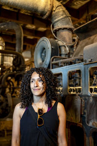 Portrait of a mixed race woman smiling while posing inside an abandoned factory.