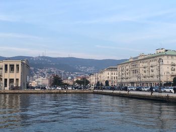 City at waterfront against cloudy sky