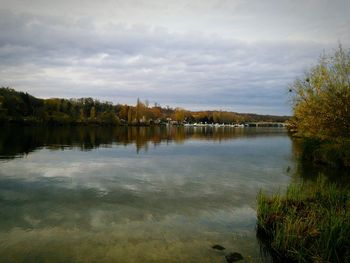 Calm lake against cloudy sky