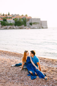 Rear view of women sitting on beach