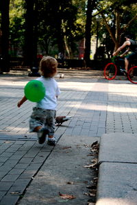 Rear view of boy riding bicycle on street