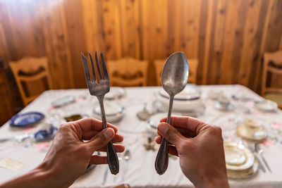 Cropped hand of person holding fork and spoon